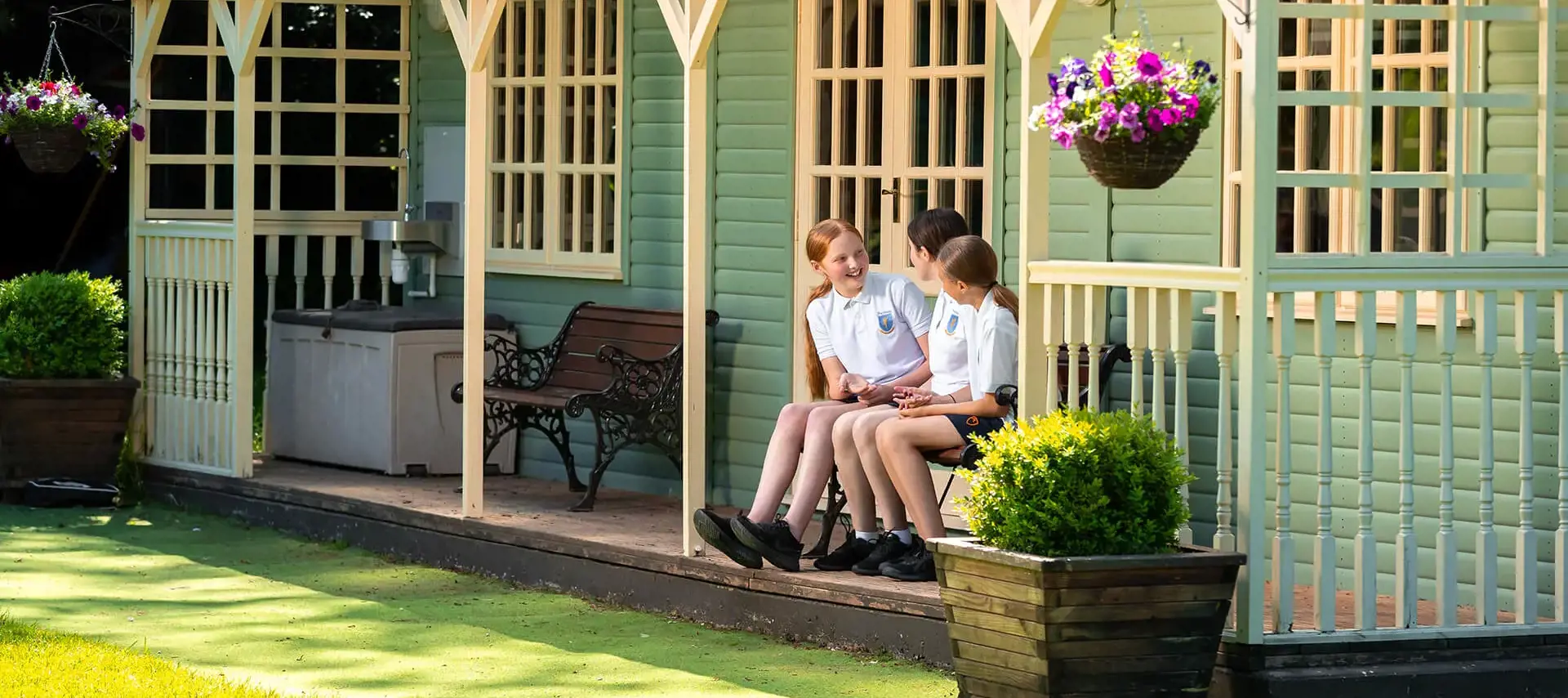 Pupils chatting in the sun at the Cricket Pavilion at The Gregg School